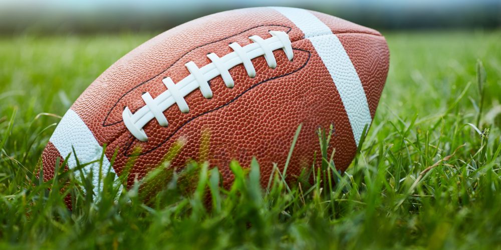 American football on green grass.
